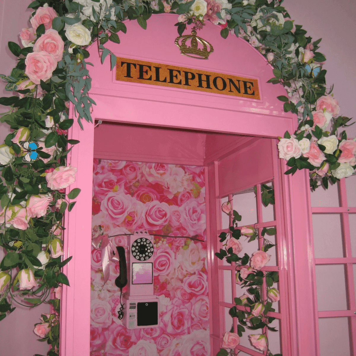 A pink telephone booth covered in roses